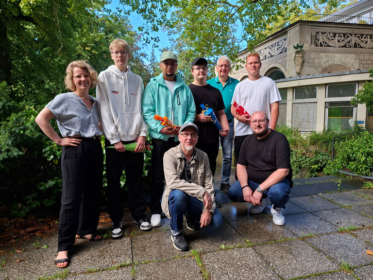 Gruppenbild der neuen Auszubildenden bei Werkstück mit Geschäftsführer und Mitarbeitenden auf der Terrasse der Wannse-Villa Gruppenbild der neuen Auszubildenden bei Werkstück mit Geschäftsführer und Mitarbeitenden auf der Terrasse der Wannse-Villa